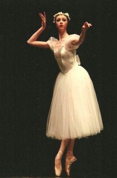 a woman in a white dress is performing on stage