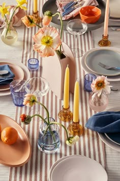 the table is set with plates, candles and flowers