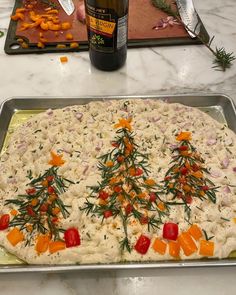 a christmas tree shaped pizza sitting on top of a pan next to a bottle of wine