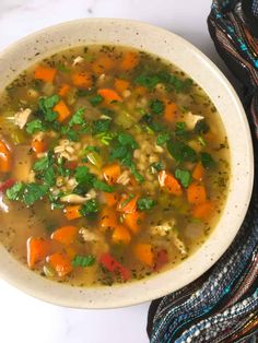 a bowl of soup with carrots, celery and parsley