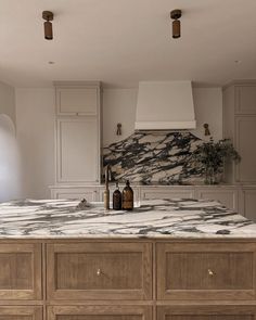 a kitchen with marble counter tops and wooden cabinets in the center, surrounded by white walls