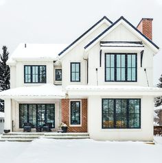 a large white house with lots of windows and snow on the ground in front of it