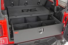 the back end of a red jeep with its trunk open and storage compartments in it