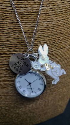 "Alice in Wonderland inspired pocket watch necklace, with resin steampunk-style White Rabbit and hand stamped quote pendant \"I'm late! I'm late! For a very important date! No time to say hello, goodbye! I'm late! I'm late! I'm late!\" Long-chain necklace with a perfectly functioning pocket watch, a stamped silver metal pendant which reads \"We're All Mad Here\" and a resin handmade pendant, featuring real steampunk clock gears, in the shape of the White Rabbit silhouette. The watch works on bat Alice In Wonderland Watch, Rabbit Silhouette, Clock Gears, Alice In Wonderland Inspired, Hello Goodbye, Steampunk Clock, Pocket Watch Necklace, Steampunk Style, Face Reveal