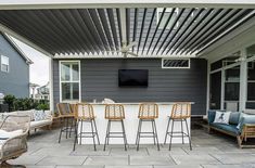 an outdoor bar with four chairs and a television mounted on the wall