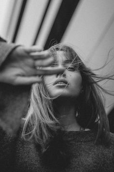 a black and white photo of a woman with her hair blowing in the wind,