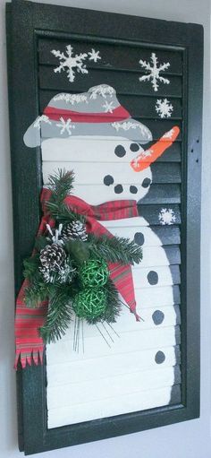 a snowman made out of shutters is hanging on the wall with pine cones