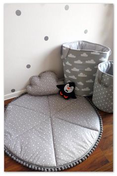 a stuffed penguin sitting on top of a bed next to two storage bins and a polka dot wall