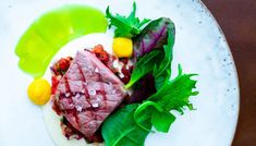 a white plate topped with meat and veggies on top of a wooden table