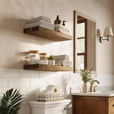 a white toilet sitting next to a wooden shelf filled with towels and other bathroom items