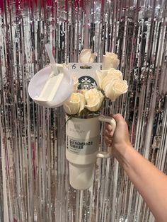 a starbucks coffee cup with flowers in it being held up by someone's hand