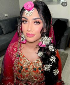 a woman wearing a red and gold outfit with flowers in her hair is posing for the camera