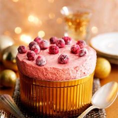 a cake with raspberries on top is sitting on a table next to silverware