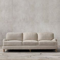 a white couch sitting on top of a wooden floor next to a wall with a potted plant