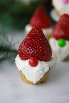 some cupcakes with white frosting and strawberries on top