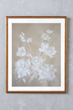 a white flower in a gold frame on a wall