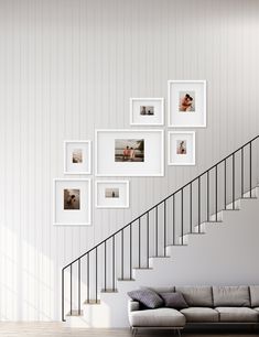 a living room with pictures hanging on the wall and stairs leading up to the second floor