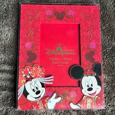 the mickey mouse and minnie mouse photo frame is shown on carpeted area with red background