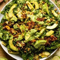 a white bowl filled with green vegetables and avocado on top of a wooden table