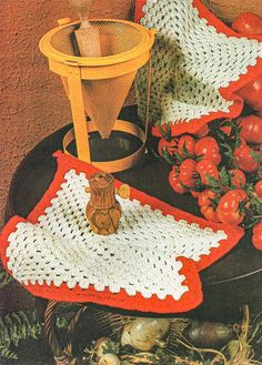 an old crocheted dishcloth and pot holder on a table with tomatoes in the background