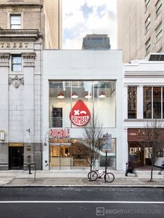 an empty street in front of a building with a bicycle parked on the sidewalk next to it