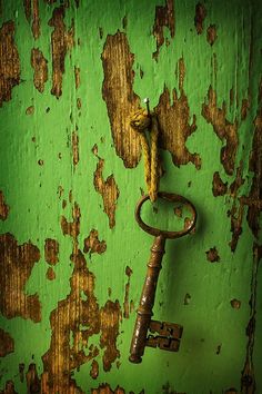 an old rusty key hanging on a green wall