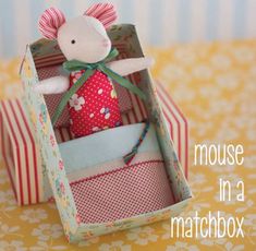 a mouse in a matchbox sitting on top of a yellow and white table cloth