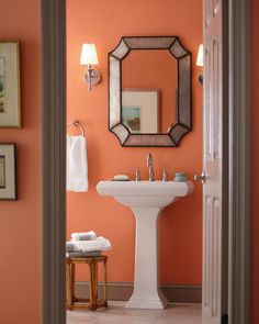 an orange bathroom with a pedestal sink and mirror