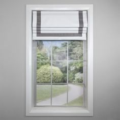 an open window with a white and gray roman blind on it's side, in front of a garden