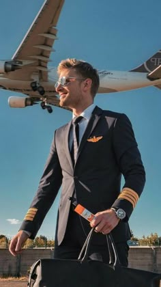 a man in a suit and tie carrying a duffel bag next to an airplane