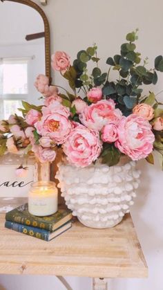 a vase filled with pink flowers sitting on top of a table next to a mirror