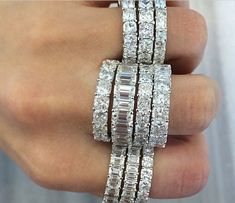 a woman's hand holding three rings with diamonds on each ring and two rows of baguetts in the middle