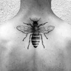 a black and white photo of a bee on the back of a man's chest