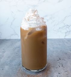 there is a drink with whipped cream on top in a glass jar next to a marble counter