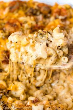 a spoon full of macaroni and cheese being lifted from a casserole dish