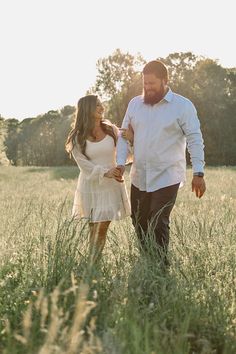 a man and woman walking through tall grass