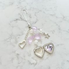 two heart shaped charms on a white marble counter with beads and charms attached to them