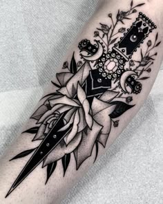 a black and white tattoo on the leg of a woman with scissors, roses and leaves