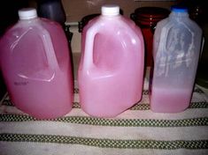 three gallon jugs of liquid sitting on top of a table