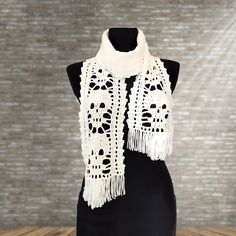 a white crocheted scarf is on a mannequin with a brick wall in the background