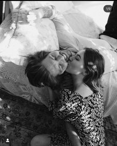 two women laying on the floor kissing each other with their noses close to one another