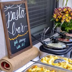 pasta bar with chalkboard sign next to it and various foods in pans on the counter