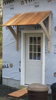 a white door sitting next to a wooden roof on top of a house under construction