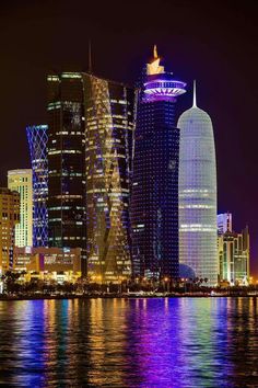 the city skyline is lit up at night with bright lights and skyscrapers in the background