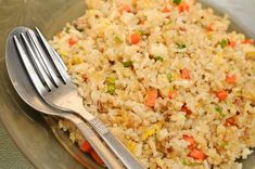 a plate with rice, carrots and peas next to a fork