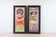 two framed pictures with children's artwork on them