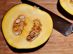 a knife cutting into a yellow squash on a wooden table with another half cut in half