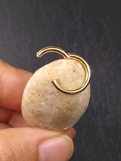 a person holding a rock with a gold ring on it's end, in front of a black background