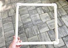 a person holding up a white frame on the ground