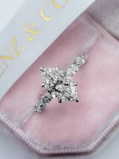 a diamond ring sitting on top of a pink velvet case